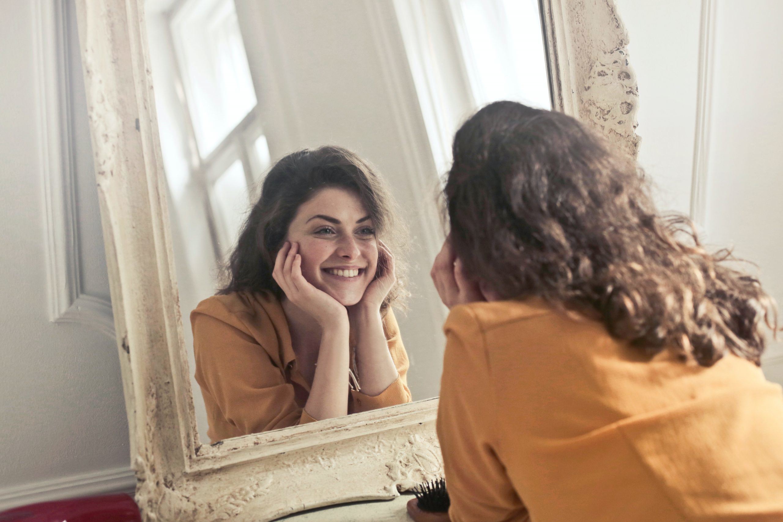 Happy woman looking at herself in the mirror