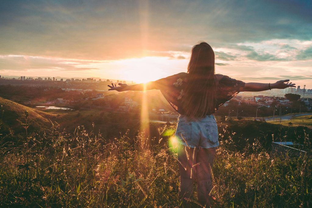 Happy woman with her arms wide open, watching the sunrise