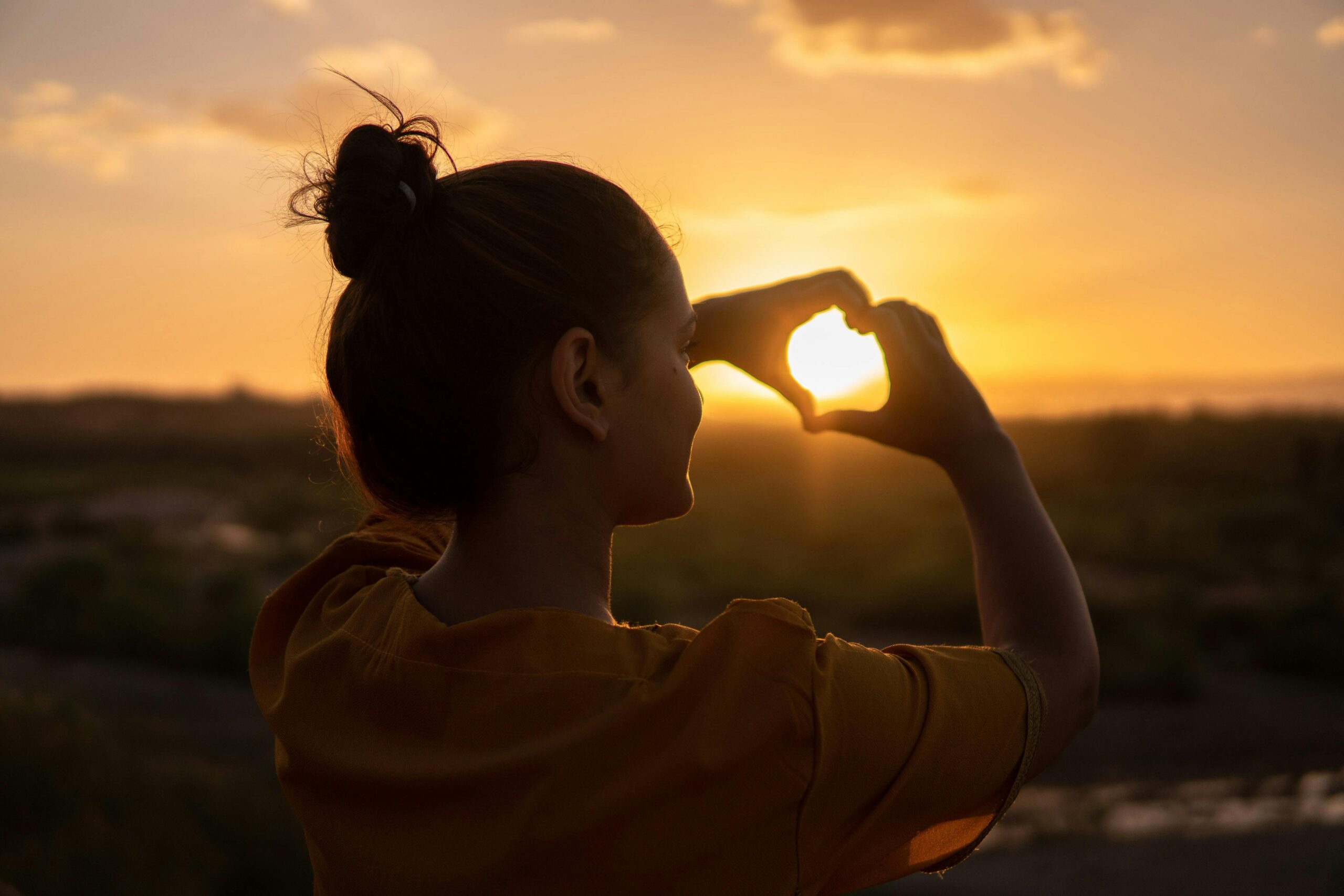 Heart hands over the sunset