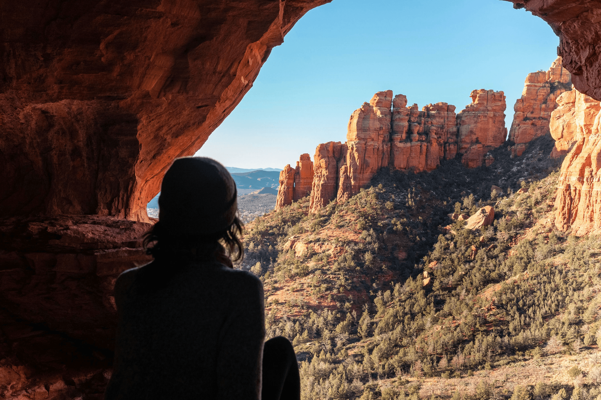 Hiker overlooking Sedona's red rocks from a cave